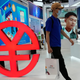 A visitor passes by a logo for the e-CNY, a digital version of the Chinese Yuan, displayed during a trade fair in Beijing, China.